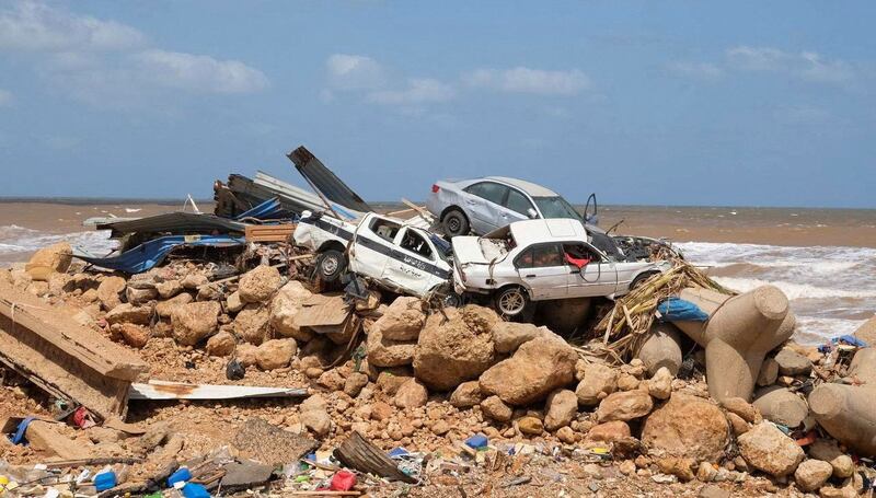 carros arrumbados a un lado de la costa junto a escombros y rocas