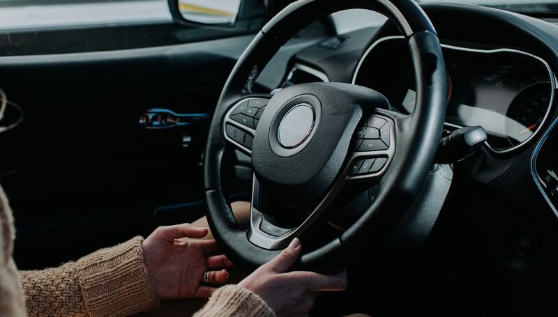 mujer sostiene el volante de un automóvil